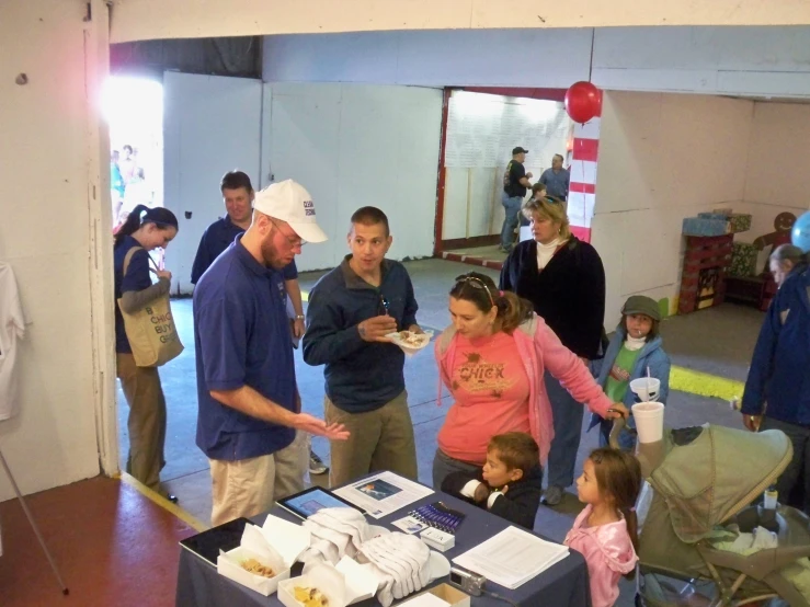 a group of people are gathered around a table with boxes and umbrellas