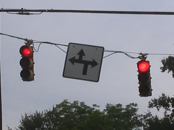 traffic lights are strung on wires under the street sign