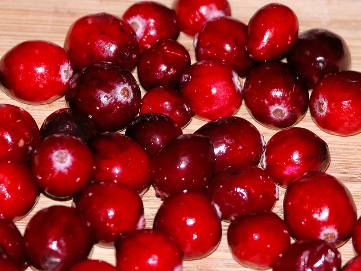 several whole cherries on a table with one partially eaten
