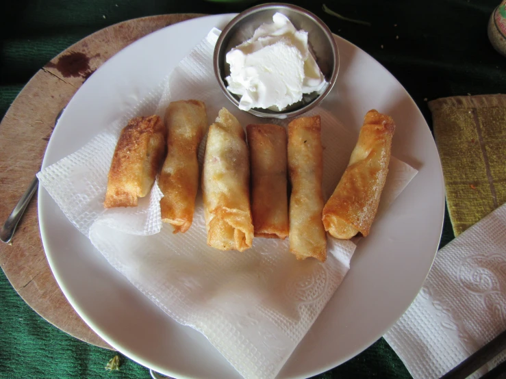 a white plate with some food and a bowl with yogurt on it