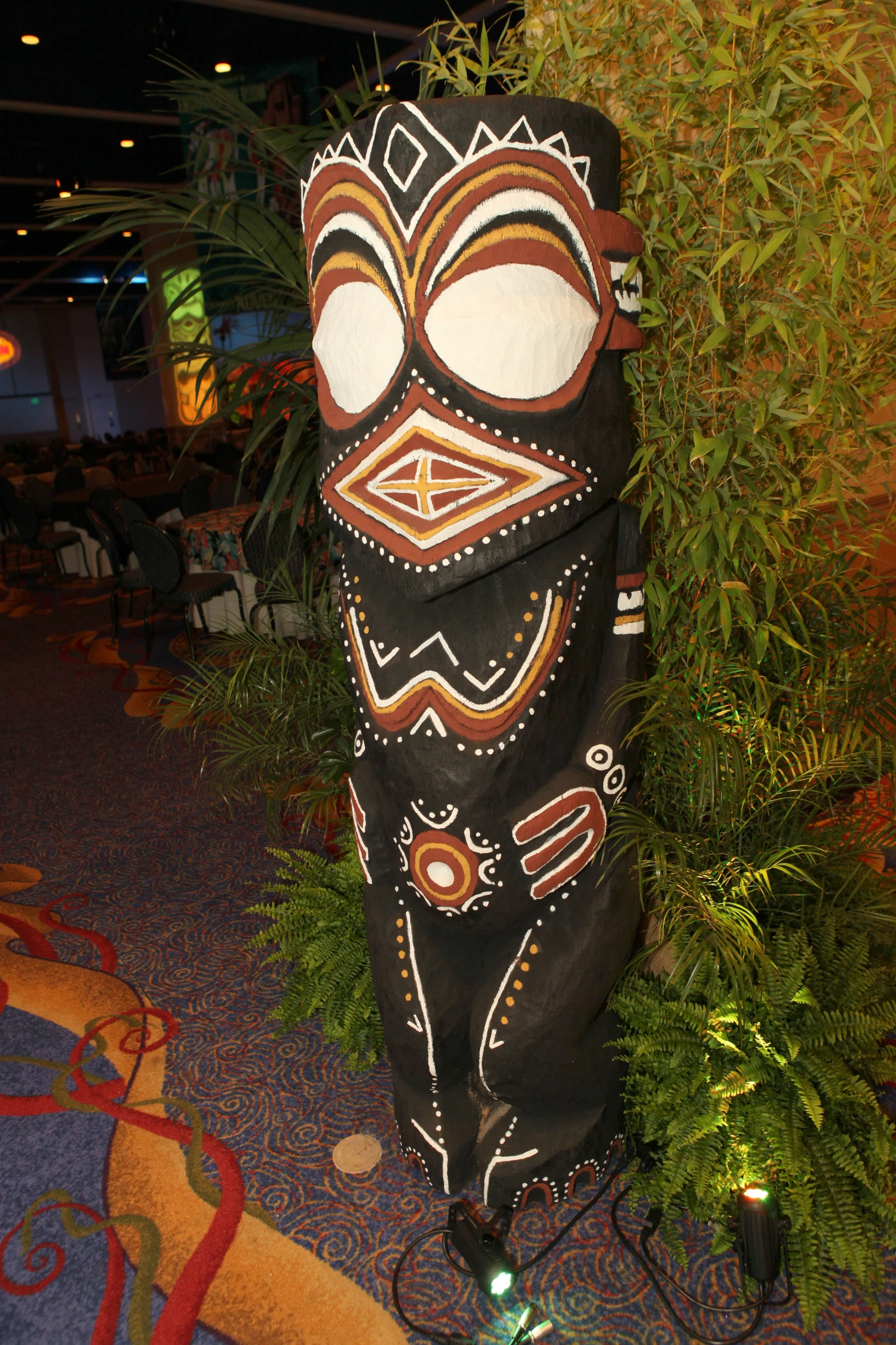 a decorative mask is sitting by a green bush