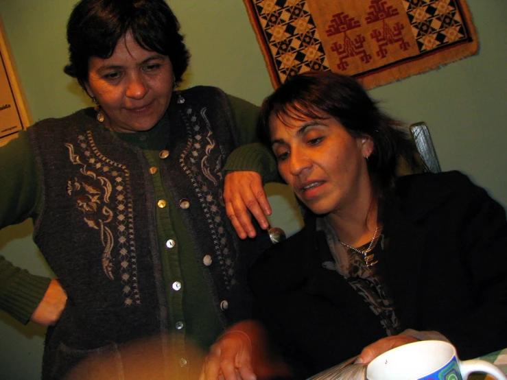 two women looking down at soing on a table