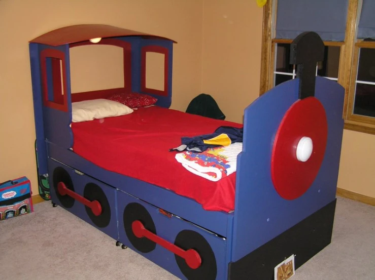 there is a small children's bed with red sheets on it