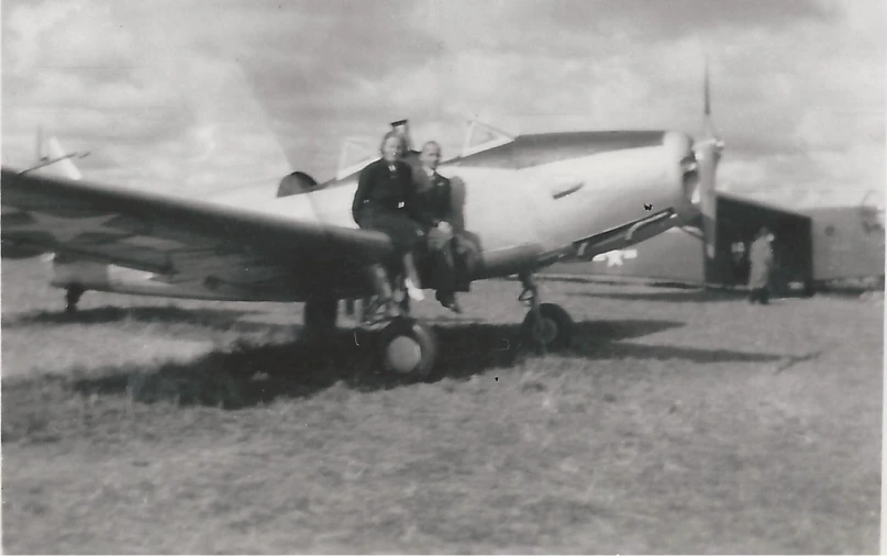 black and white po of two men sitting on a small airplane