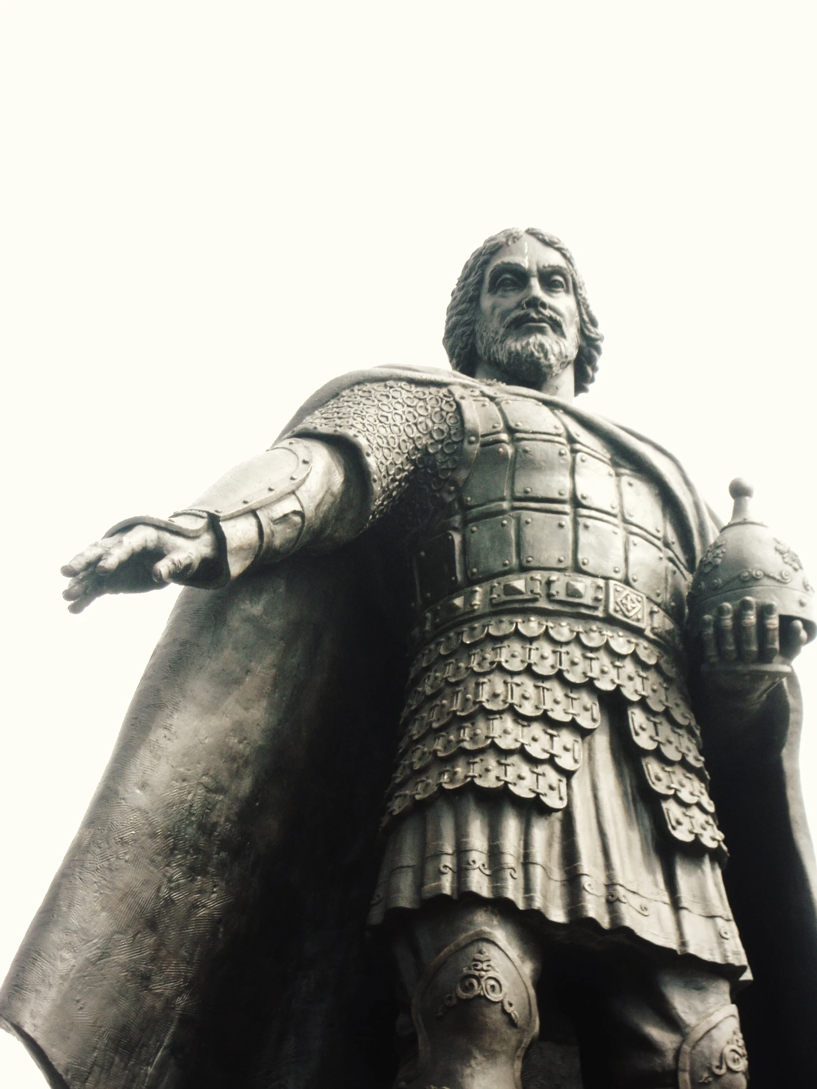 a statue in front of a sky background wearing armor