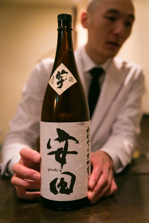 a person in a tie sitting at a table with a bottle