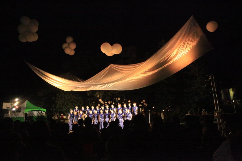 performers perform under a canopy in front of an audience at night