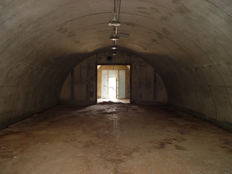 light coming into an old cement tunnel with one light on