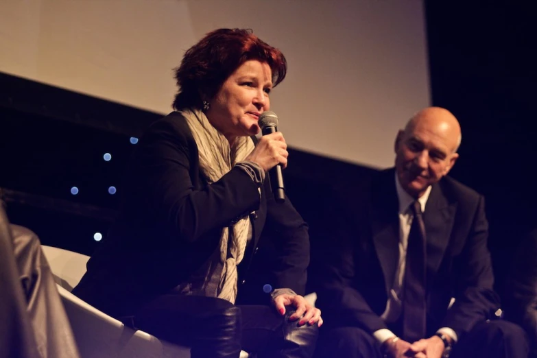 two people sitting on chairs while holding a microphone