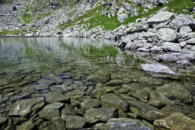 there is a small body of water next to rocks and grass