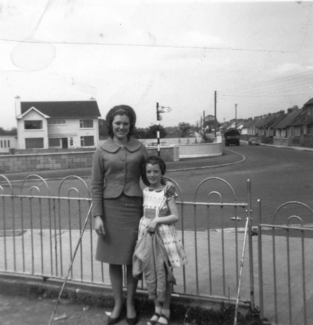 two women and a  posing in front of a fence