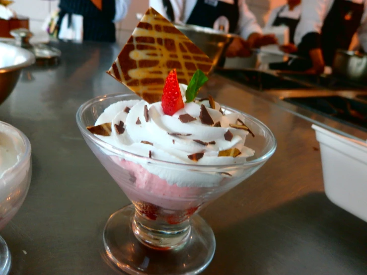 dessert dish in small glass on countertop with people behind