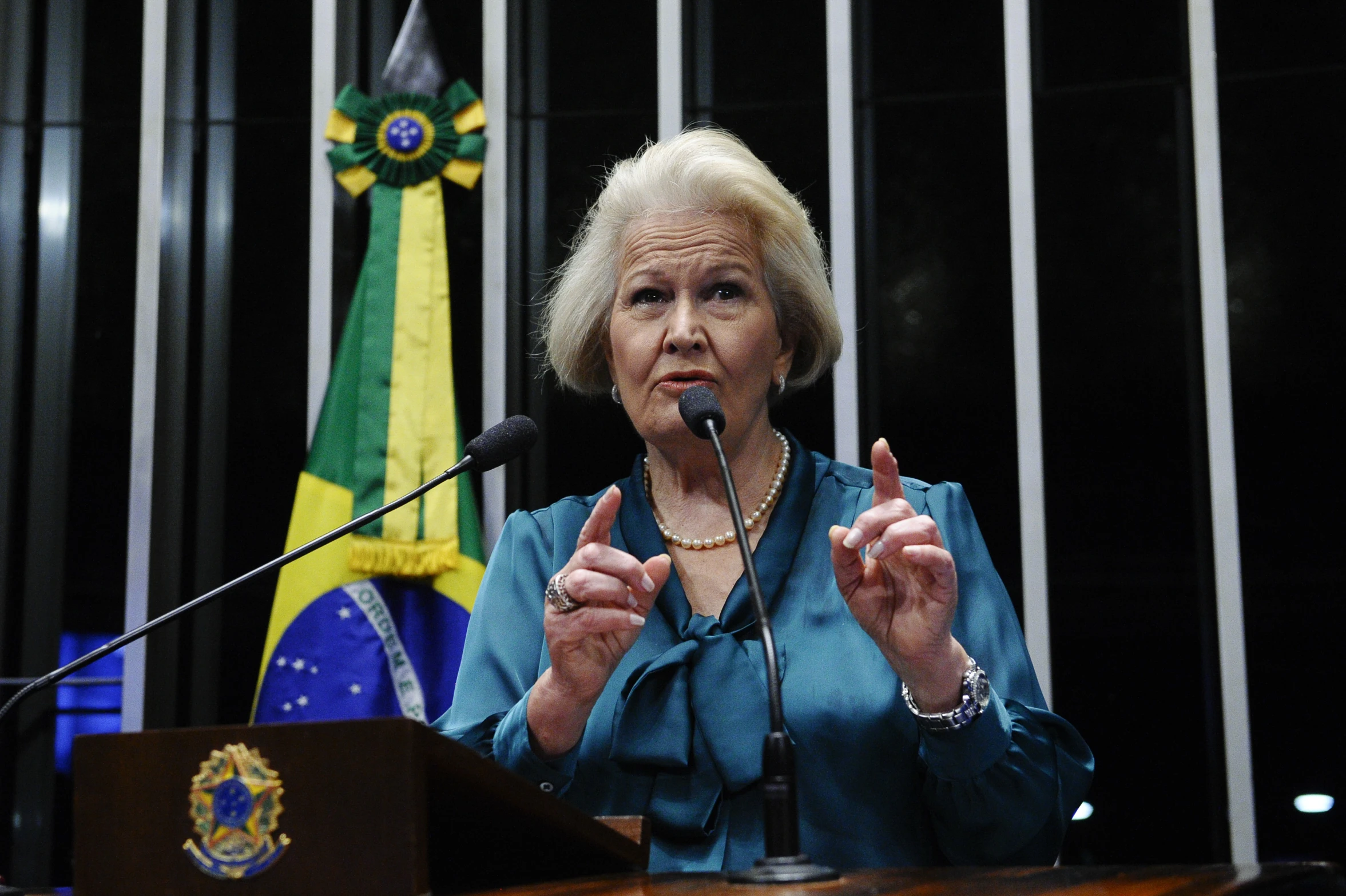 woman speaking with hands in the air while standing at the podium