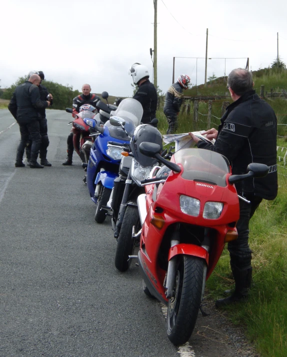 four people stand around and look at a row of motorcycles