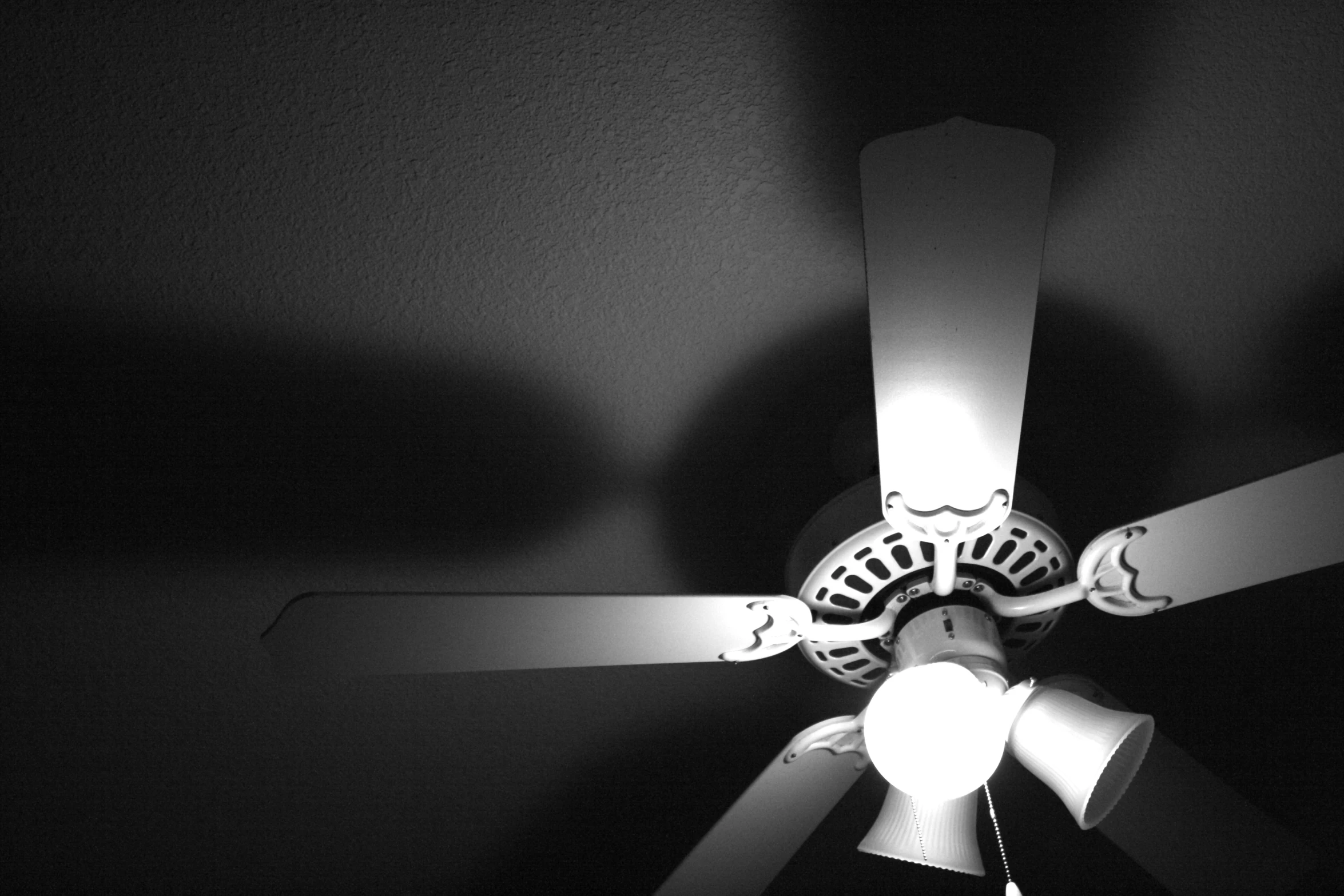a ceiling fan with a light on in a dark room