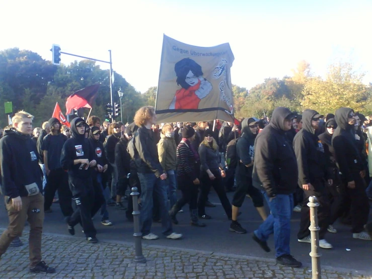 people march down a street holding flags and placards