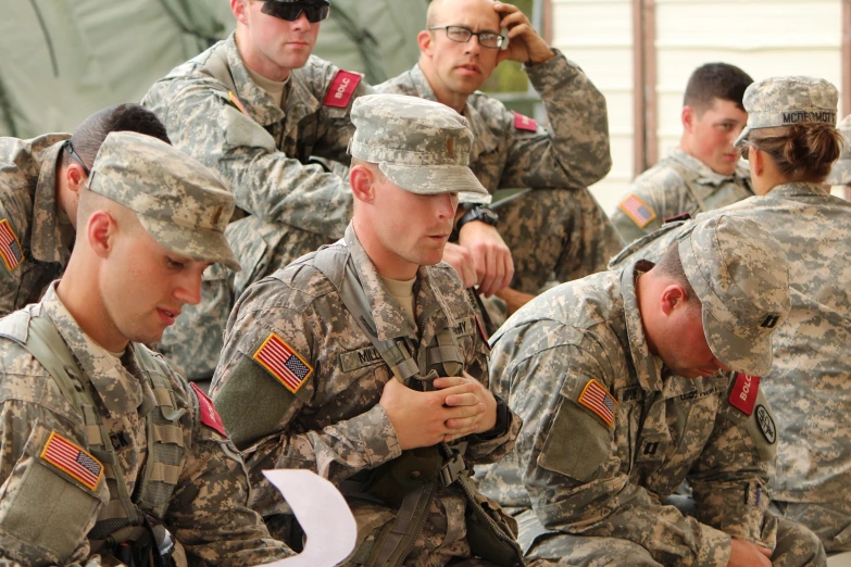 many military men wearing uniforms are looking at papers