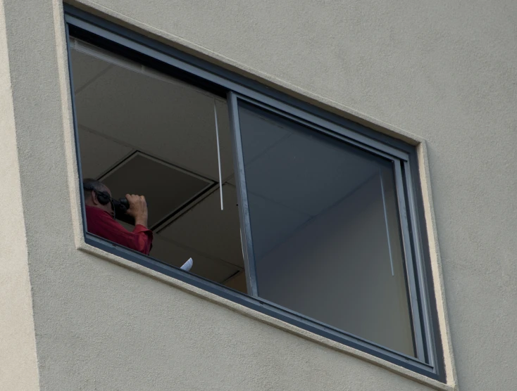 a man looking out the window with his camera