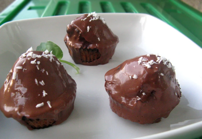 three chocolate covered muffins sitting on a white plate