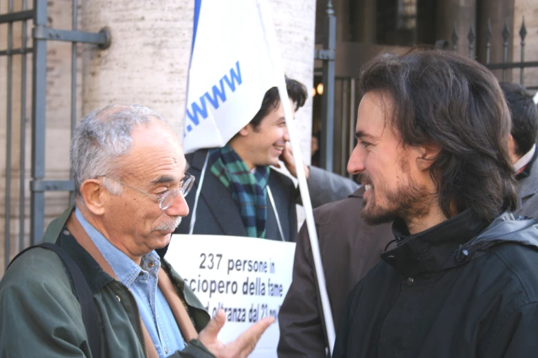 two men standing outside and one holding up a sign