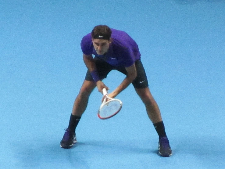 a man is bending down on the tennis court