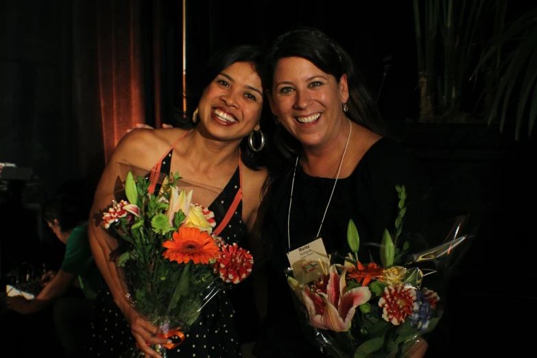 two women are holding bouquets of flowers and smiling