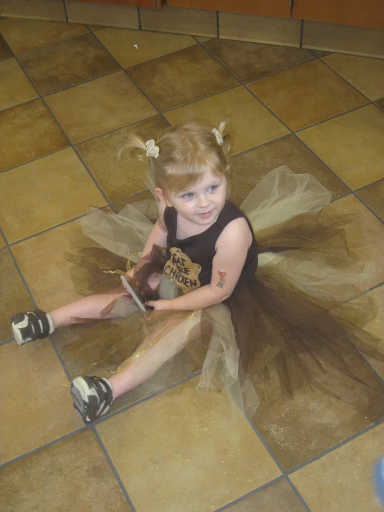 a little girl in a tutu with a cell phone