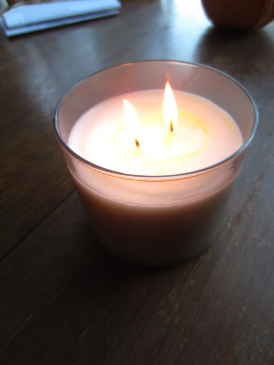 a small glass candle is lit on a wooden table