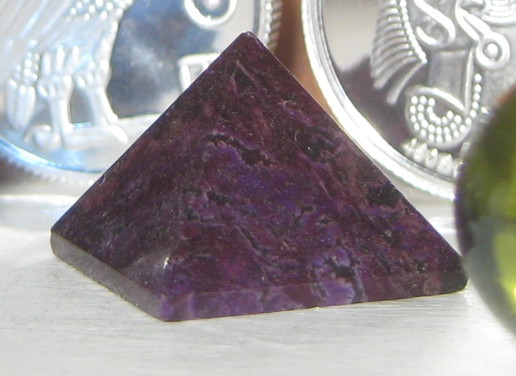 a purple stone next to a purple crystal pyramid and dollar coin