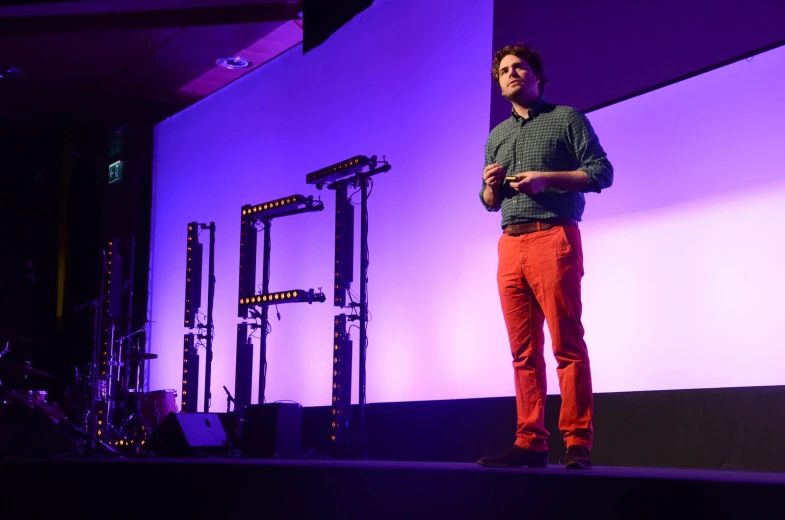 a man standing on stage in front of a projection screen