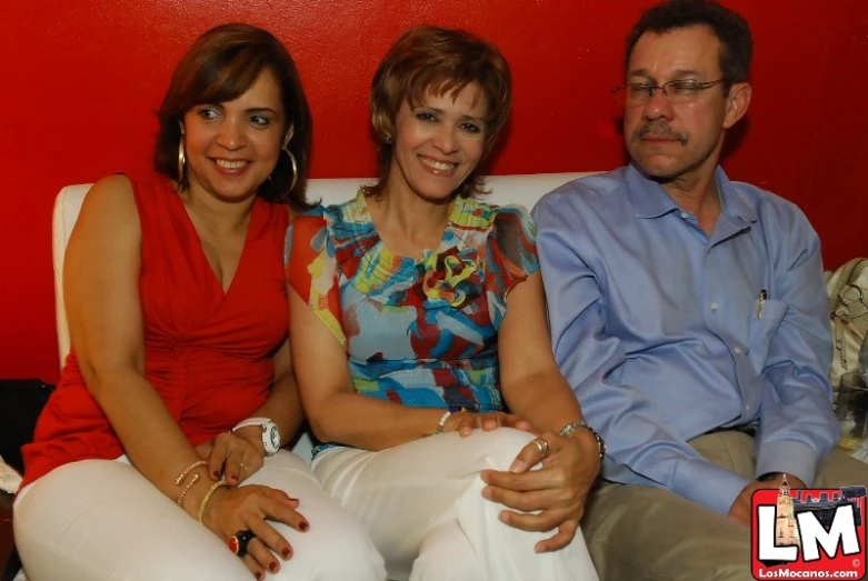 the two women are wearing white pants and sitting next to a man