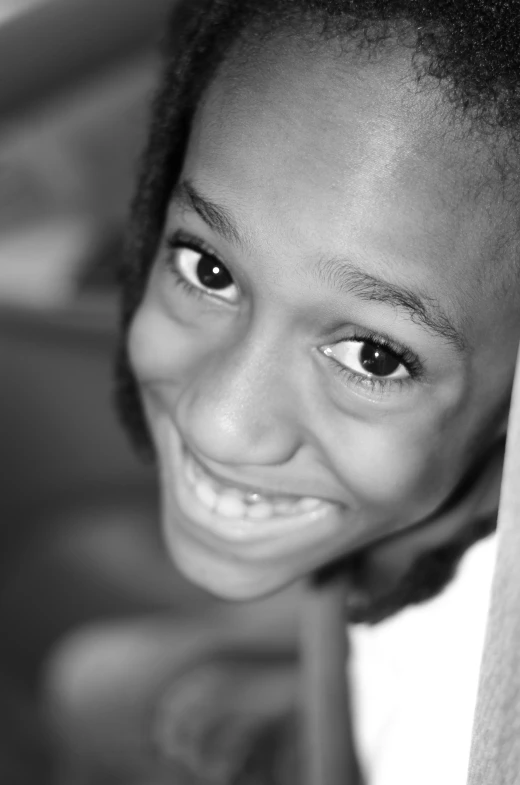 a smiling young black girl peeking out from behind the fabric