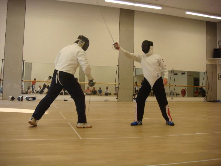 two men are preparing to compete fencing in an indoor court