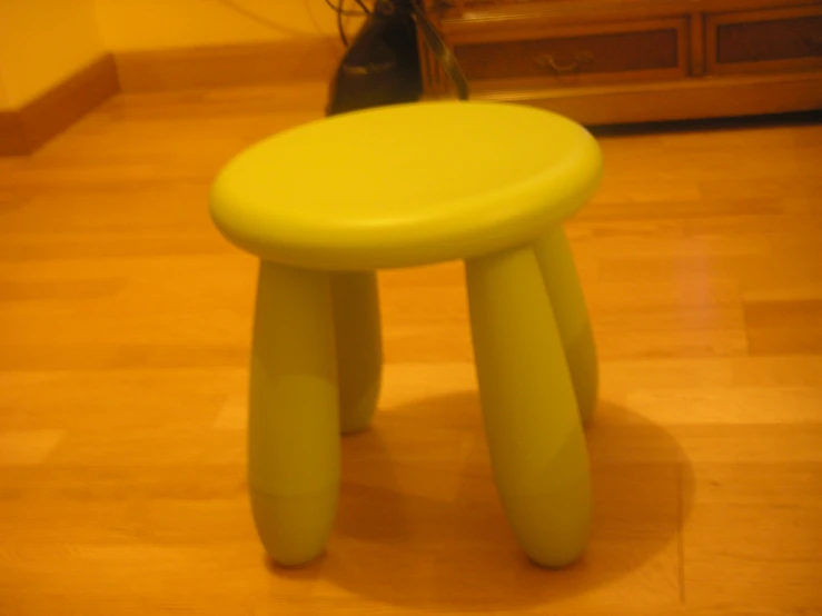 an empty stool on the floor next to a wood dresser