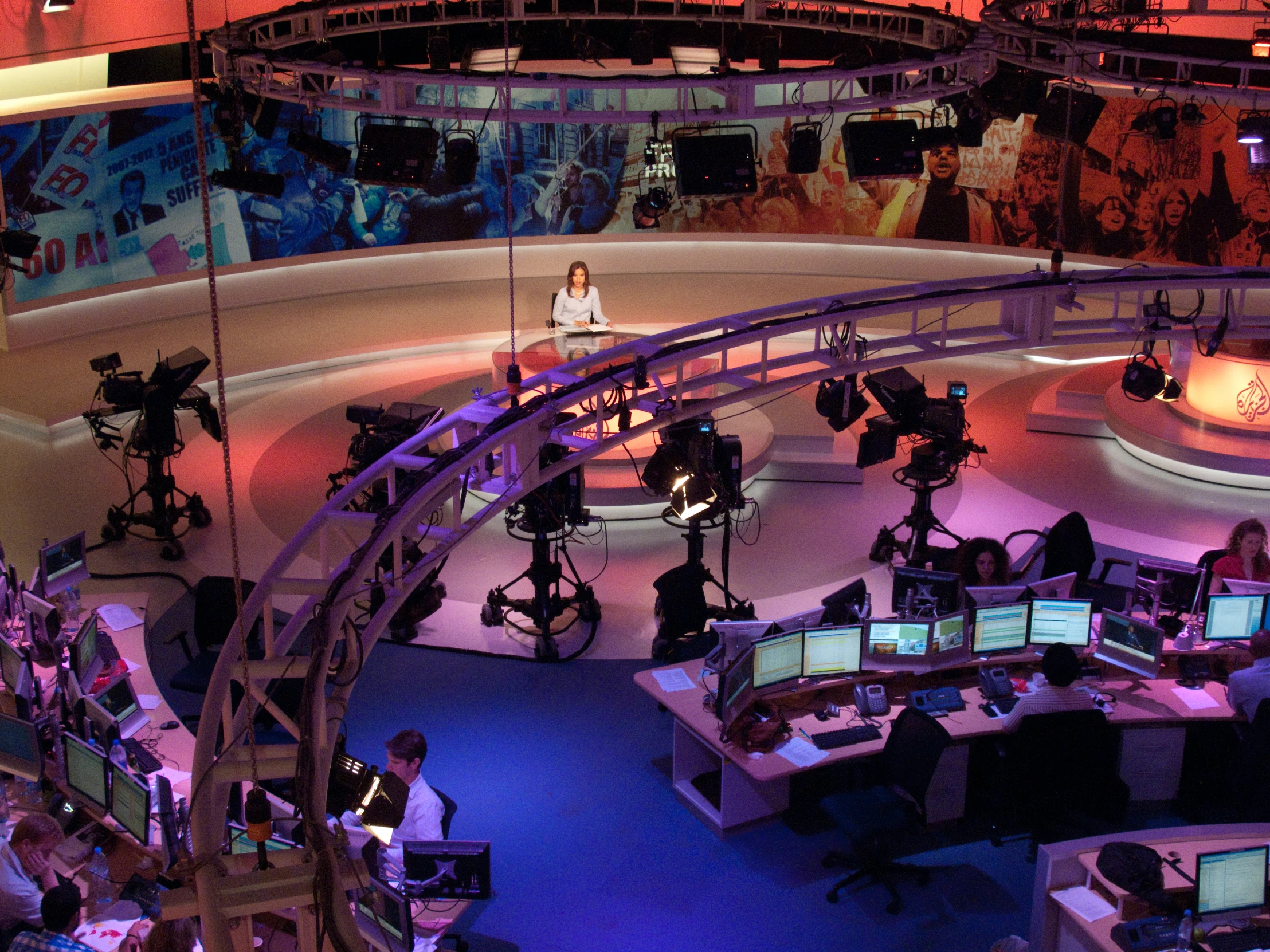 a man sitting at a large desk in an office filled with monitors