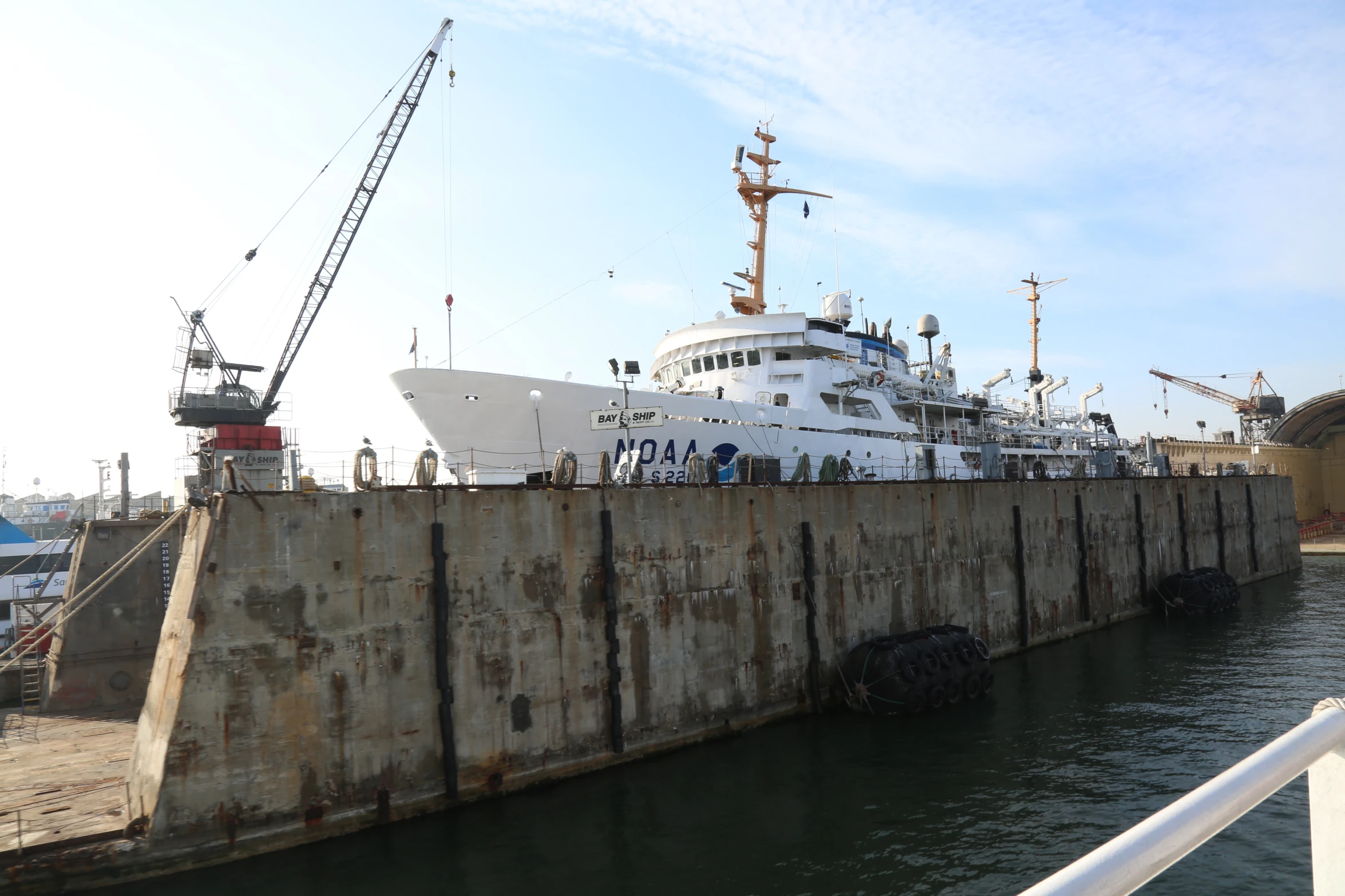 a large ship docked at a harbor with several construction workers near it