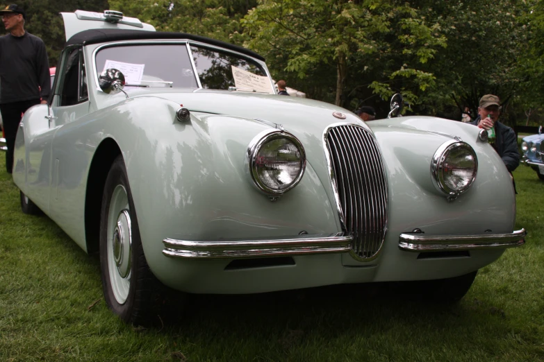 the front of an old classic car in grassy area