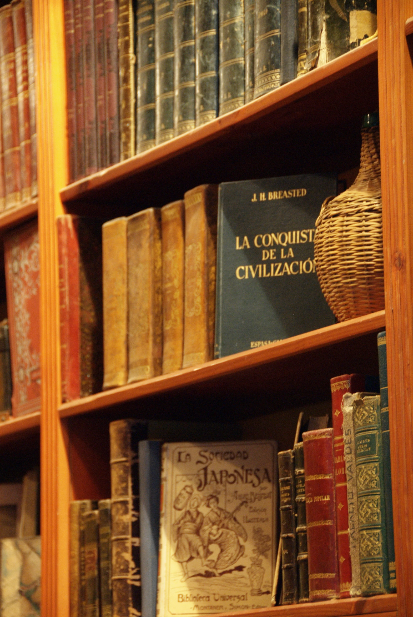 an organized bookshelf filled with lots of old books