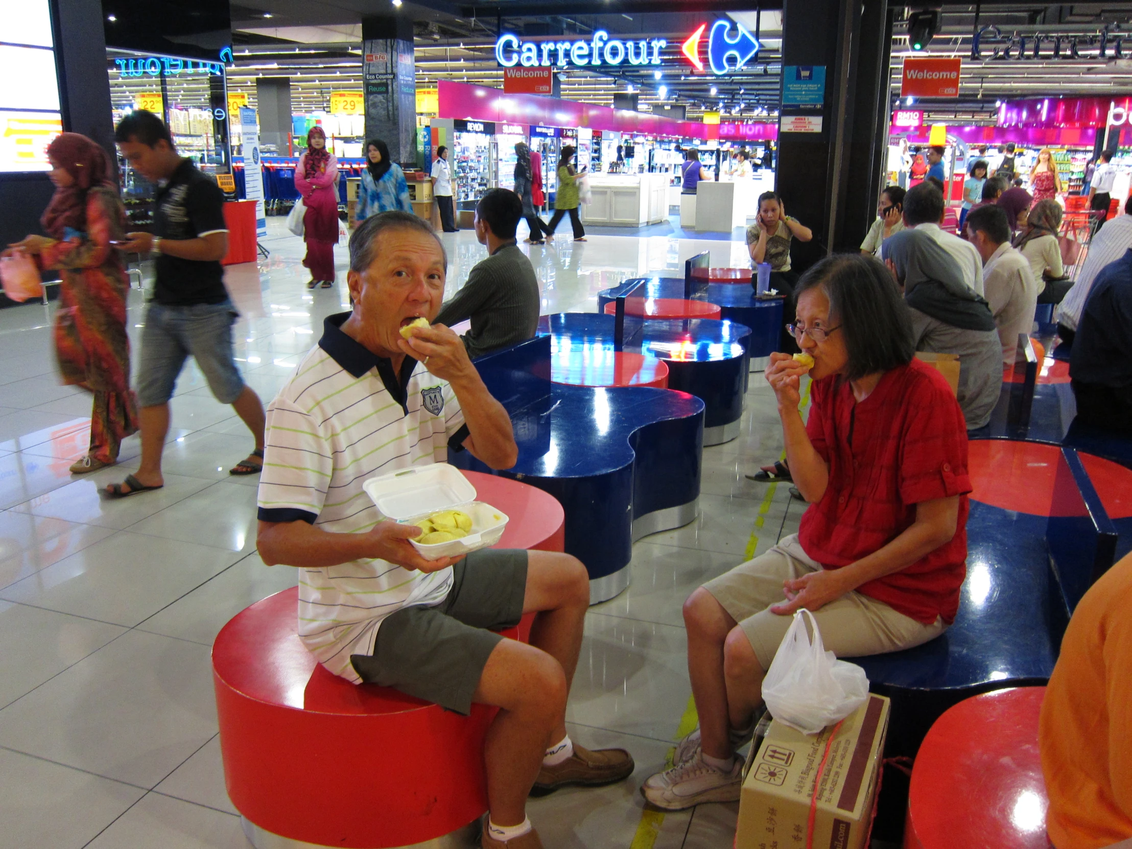 two people eating while others shop for food