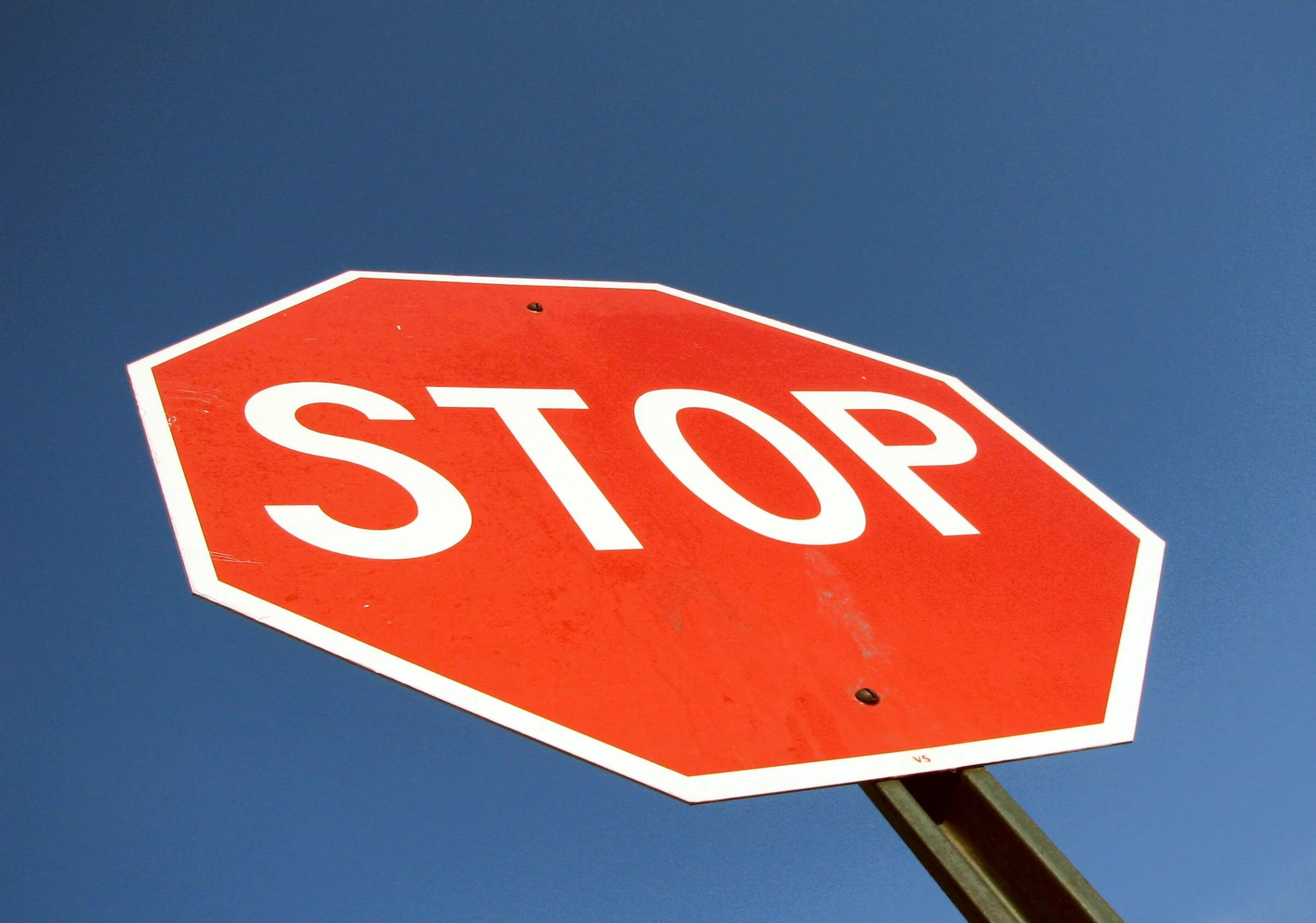 a stop sign at an intersection with a blue sky background