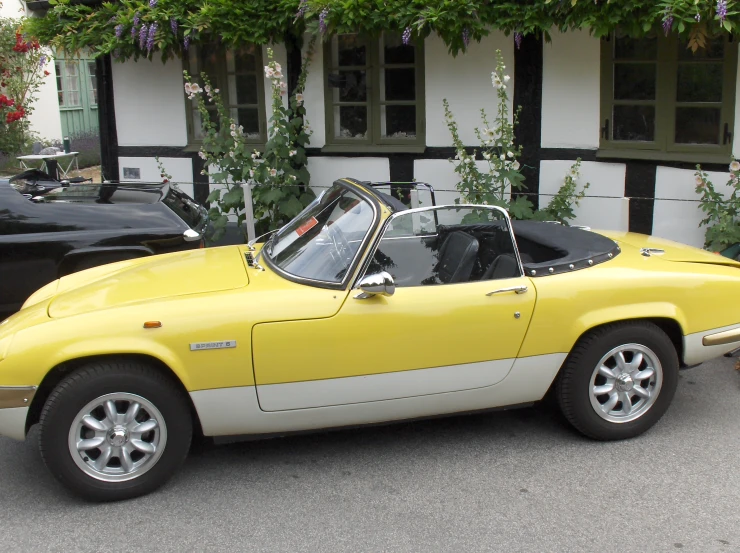 the sports car is yellow in color, with a black convertible