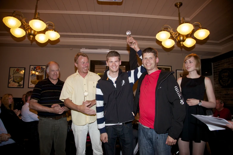 four men posing for a po together as they hold up nintendo wii controllers