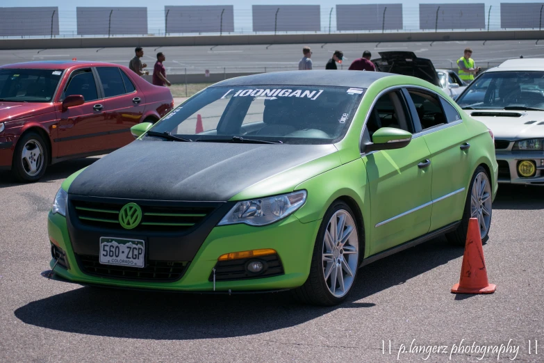 a green car is parked next to a barrier