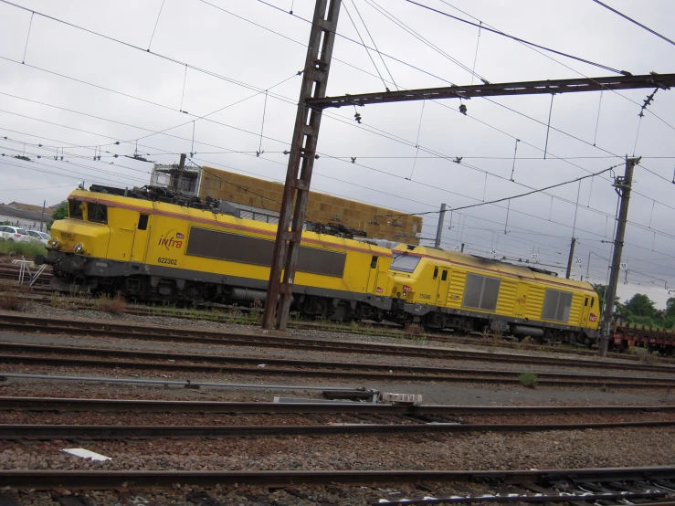 a yellow train parked in a lot next to some power lines