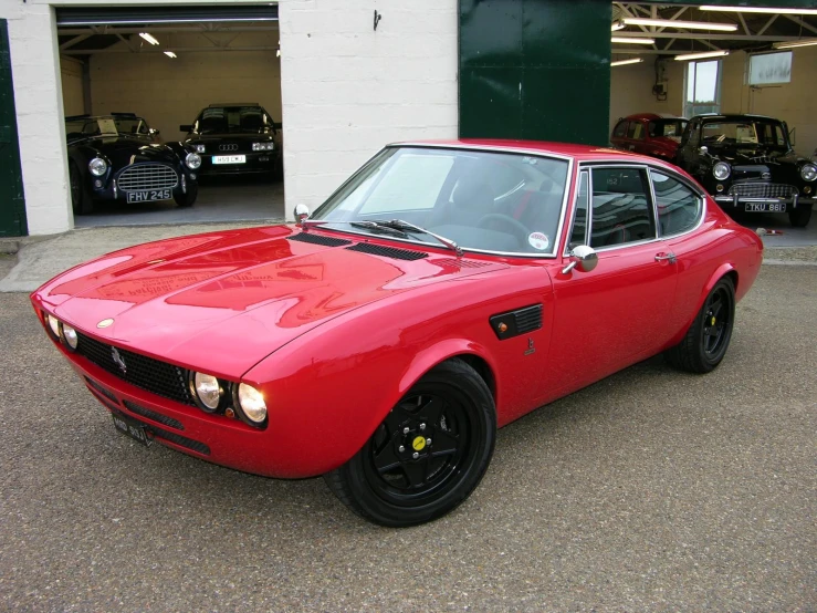 red sports car in the parking lot of an automobile repair shop