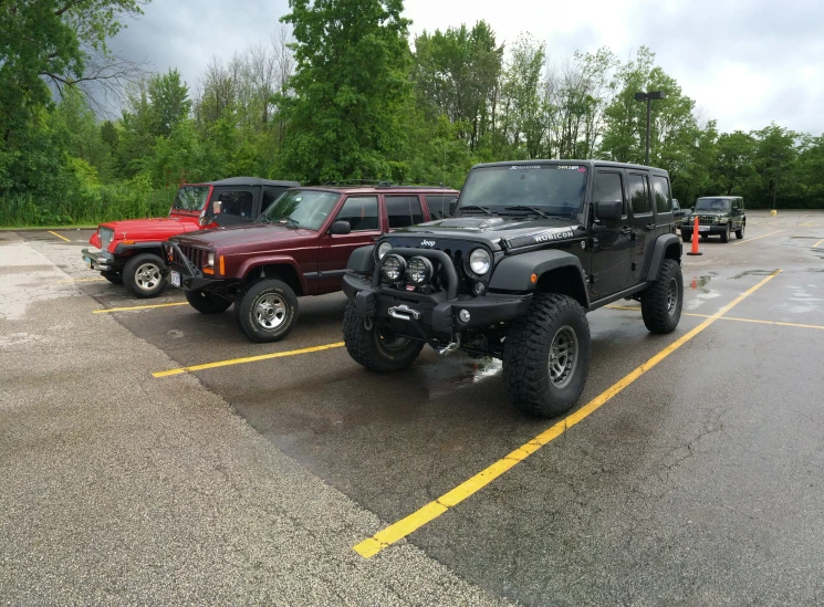 two jeeps parked in a parking lot near another jeep