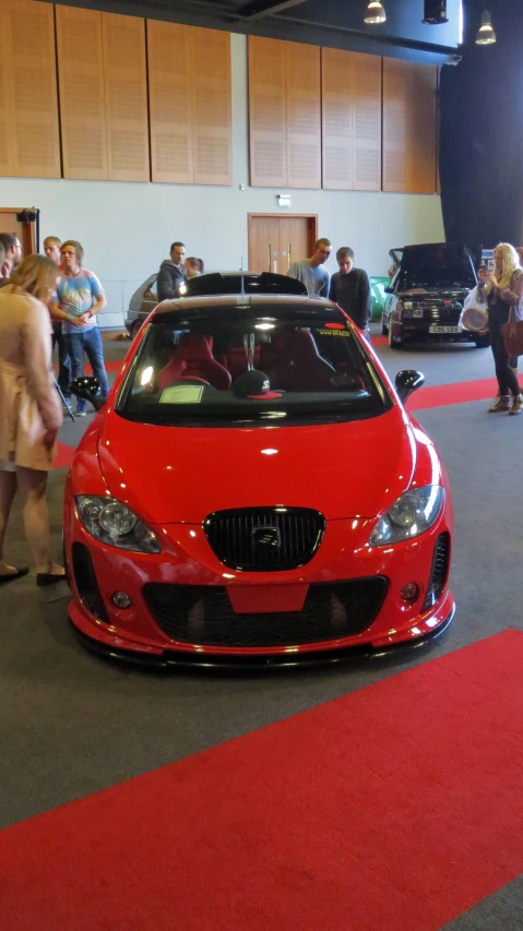 a red sports car parked next to people in a building