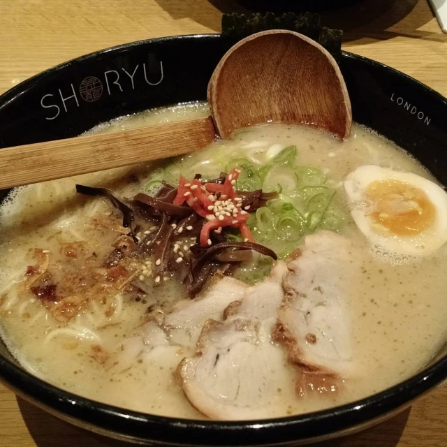 a bowl filled with rice and topped with meat, eggs, lettuce, and tomato