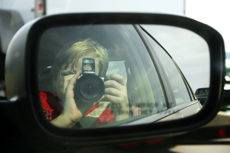 a person taking a picture in the side mirror of their car