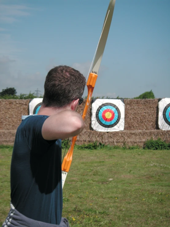 a young man holding a giant archery target with his hand